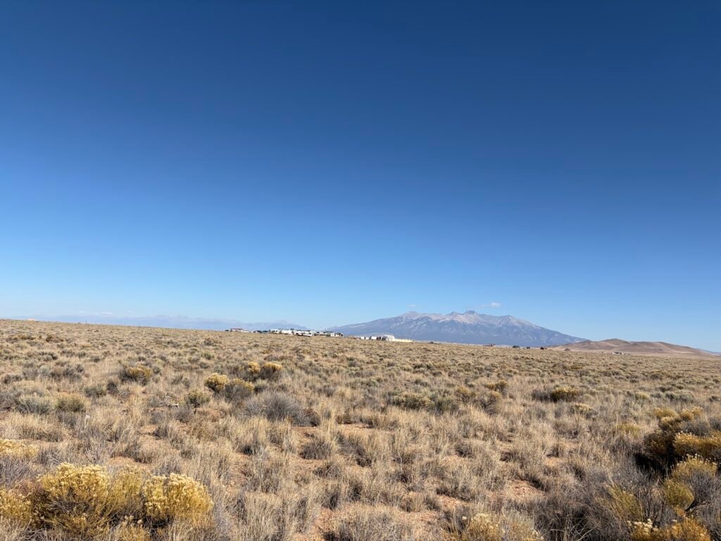 Vast Southwestern desert plateau with dense sagebrush cover under large, fluffy white cumulus clouds.
